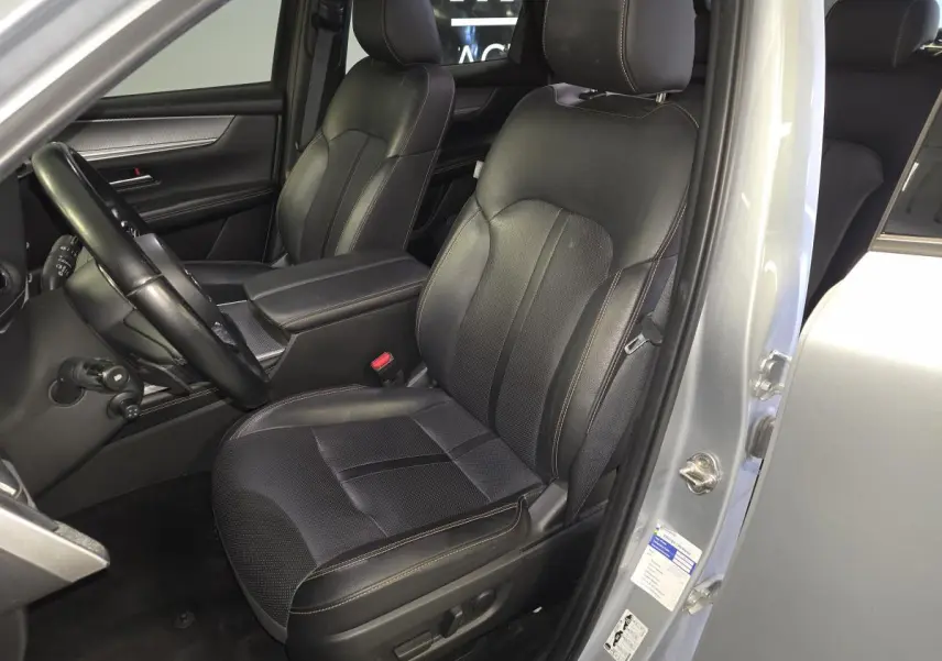 Vue intérieure côté conducteur du Mazda CX-60 gris, sièges cuir noir avec surpiqûres bronze et volant multifonction.