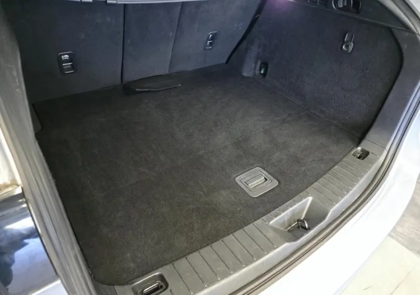 Vue rapprochée du coffre gris clair du Mazda CX-60 2.5 e-Skyactiv PHEV, montrant le tapis de sol et les fixations.