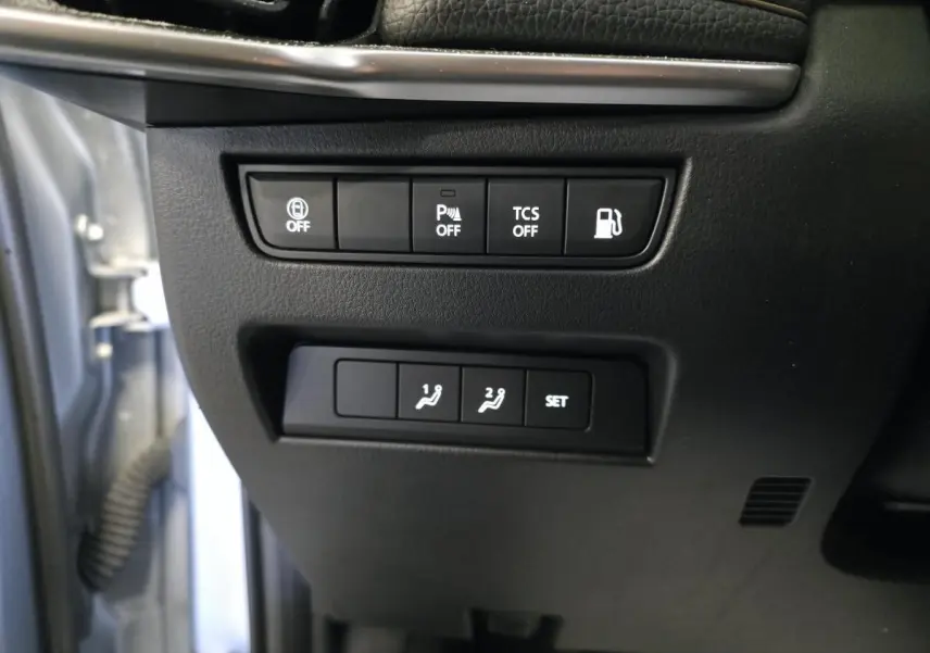 Gros plan sur les commandes noires côté gauche du tableau de bord du Mazda CX-60 gris 2023, boutons d'assistance et réglages mémoire.