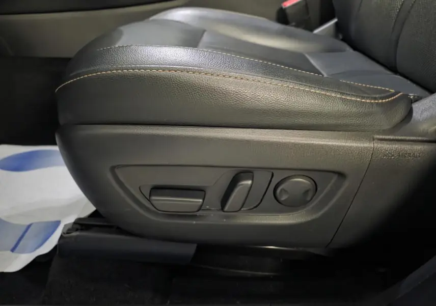 Gros plan sur les commandes électriques du siège avant en cuir noir avec surpiqûres bronze du Mazda CX-60 gris.