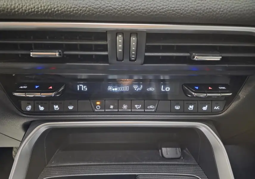 Vue rapprochée de la console centrale du Mazda CX-60 gris, montrant les commandes de climatisation et les aérateurs.