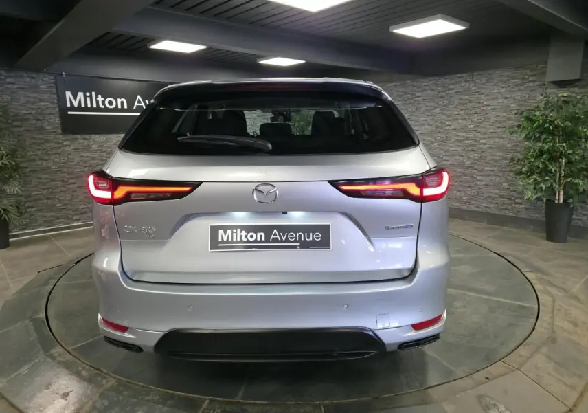 Vue arrière d'un Mazda CX-60 gris Sonic Silver 2023 avec feux LED et logo Mazda visible en intérieur showroom.