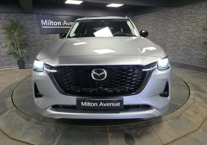 Vue frontale d'un Mazda CX-60 gris Sonic Silver avec calandre noire nid d'abeille et phares LED allumés.
