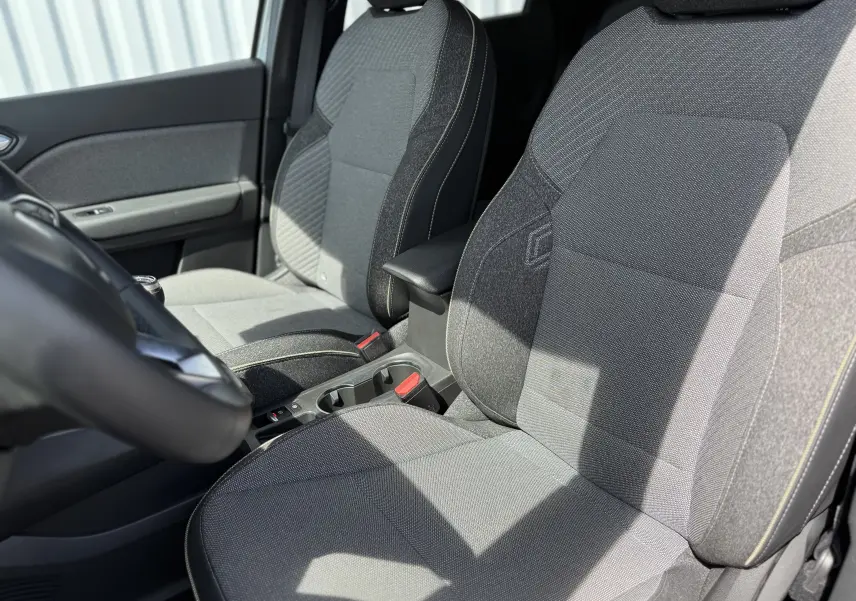 Vue rapprochée des sièges avant gris du Renault Captur 2025, avec accoudoir central et détails de couture visibles.