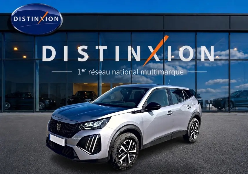 Peugeot 2008 gris 3/4 avant droit avec toit noir et jantes distinctives, devant showroom Distinxion.