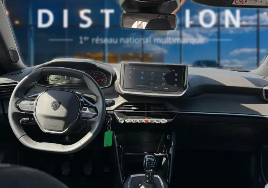 Vue intérieure du tableau de bord du Peugeot 2008 gris 2025, avec volant multifonction et écran tactile central.