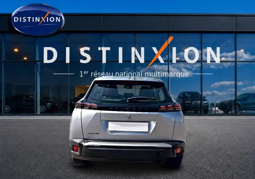 Vue arrière d'un Peugeot 2008 gris 2025 garé devant une vitrine avec logo Distinxion.