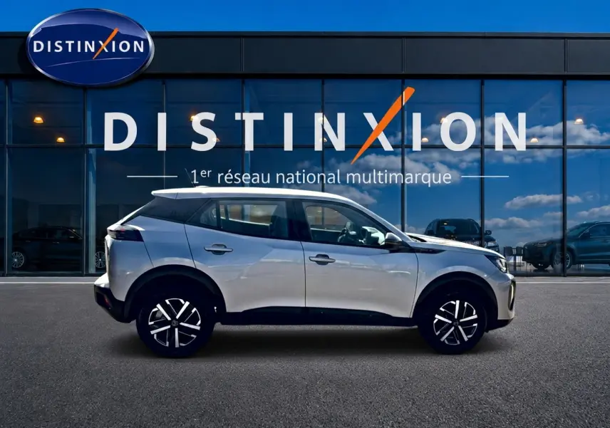 Peugeot 2008 gris en profil droit, avec jantes noires et toit blanc devant vitrine Distinxion.