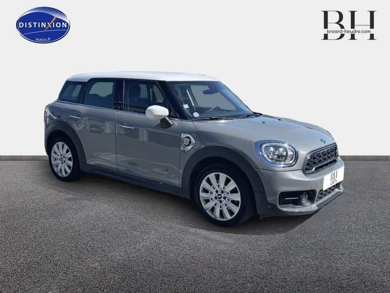 Vue 3/4 avant droite d'une MINI Countryman Cooper SE hybride gris Moonwalk avec toit et rétroviseurs blancs.