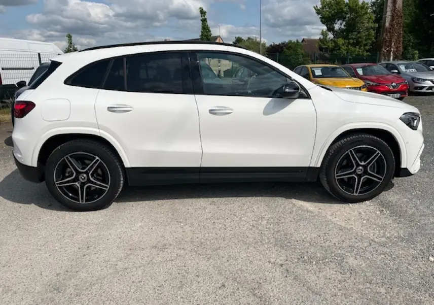 Profil côté gauche d'un Mercedes GLA blanc 2024 avec jantes AMG noires et rétroviseurs noirs brillants.