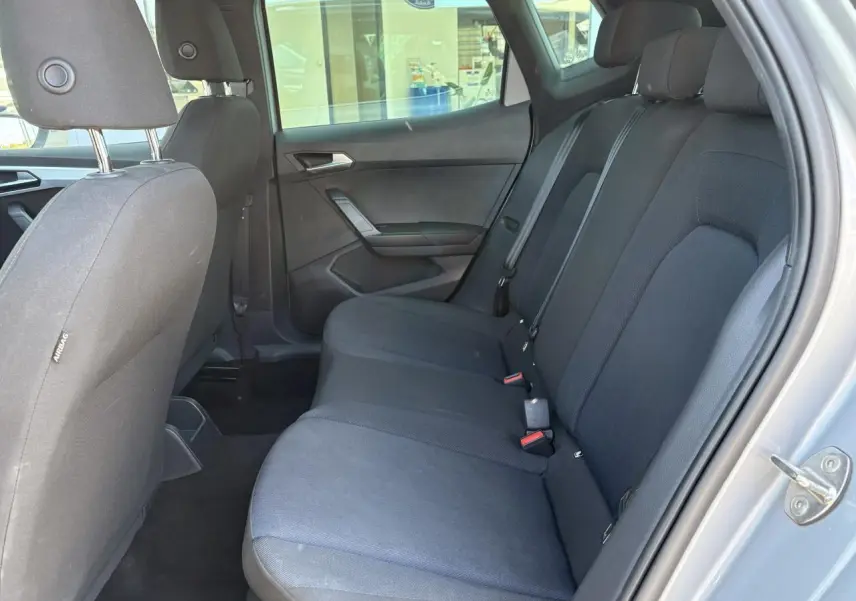 Vue intérieure côté droit sur la banquette arrière textile noire du SEAT ARONA 2024 avec appuie-têtes et ceintures visibles.