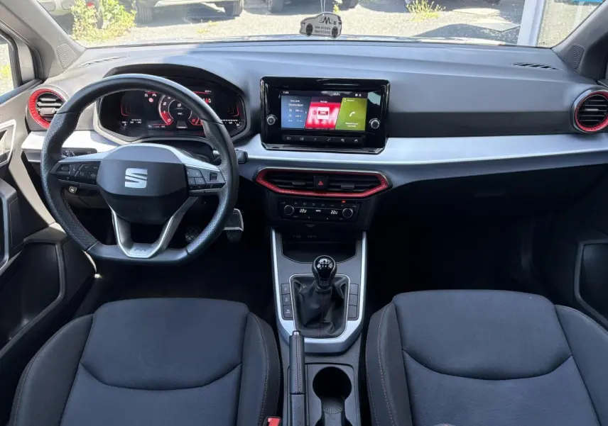 Vue intérieure frontale du tableau de bord de la SEAT Arona 2024 avec volant sport cuir et écran tactile 8,25 pouces.