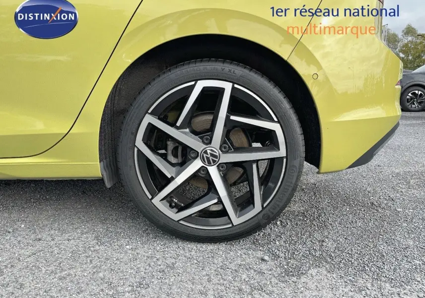 Gros plan sur la roue arrière droite d'une Volkswagen Golf jaune 2020 avec jante alliage noire et argentée.