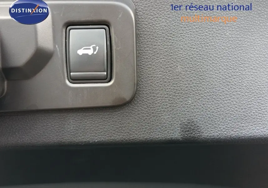 Gros plan sur le bouton d'ouverture du coffre dans l'habitacle du Renault Espace gris schiste 2024.