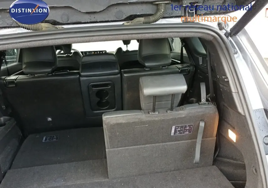 Vue arrière du coffre ouvert d'un Renault Espace gris schiste métal, montrant les sièges arrière partiellement rabattus et l'éclairage intérieur.