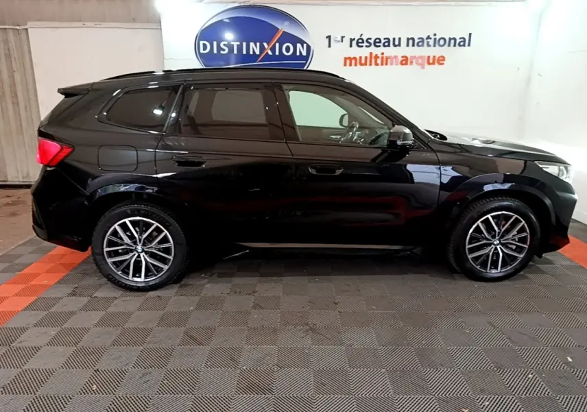 BMW X1 xDrive23i M Sport noir, vue profil côté gauche, jantes alliage et vitres teintées visibles.