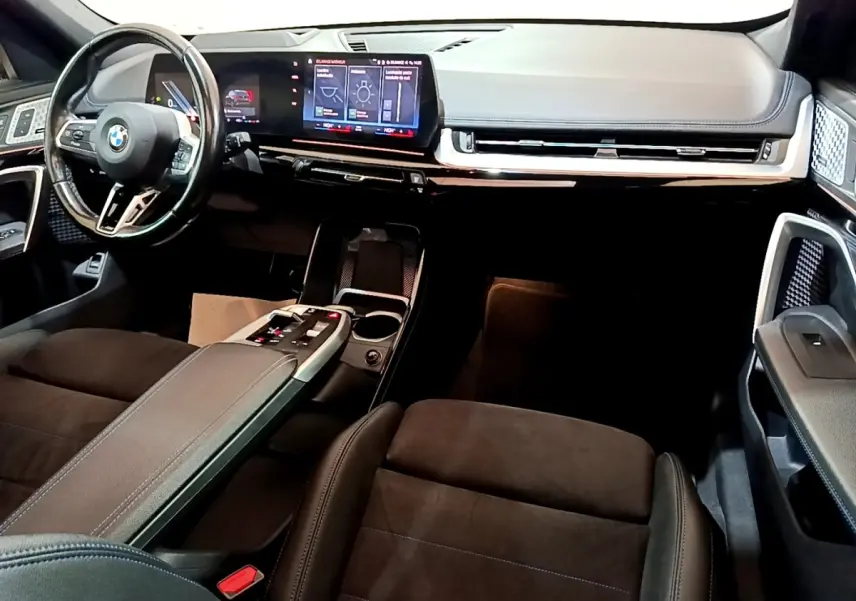 Vue intérieure avant droite du BMW X1 xDrive23i M Sport 2023, tableau de bord numérique et volant cuir noir.