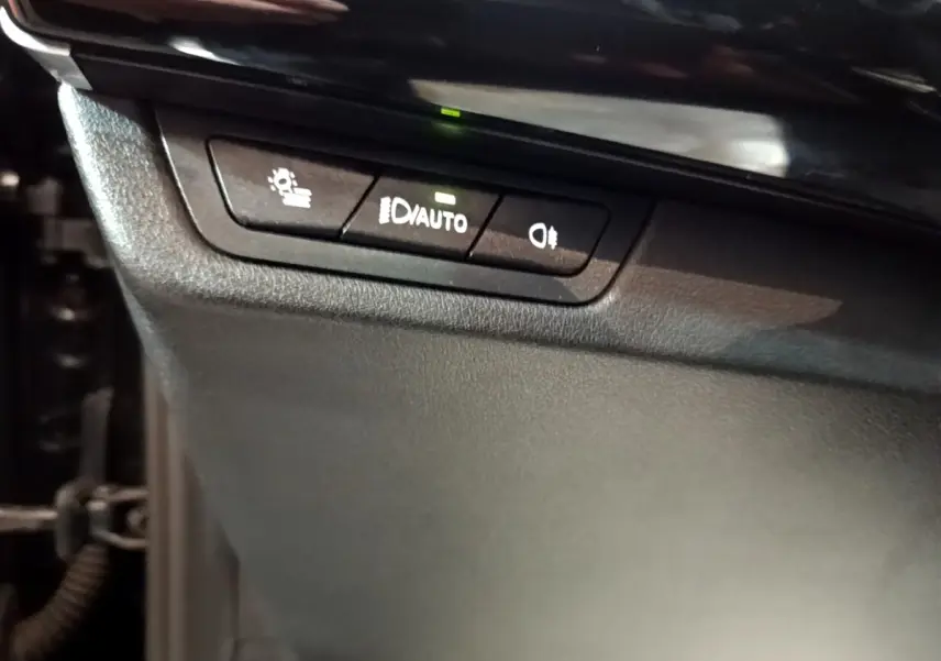 Détail des commandes d’éclairage avec bouton auto, dans l’habitacle noir d’une BMW X1 xDrive23i M Sport 2023.