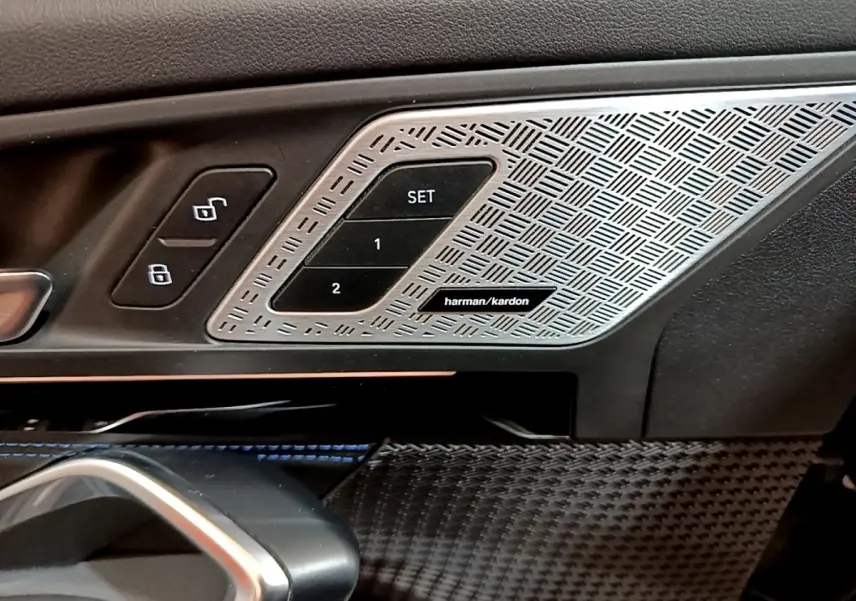 Détail intérieur côté conducteur BMW X1 noir 2023, commandes mémoire siège et haut-parleur Harman Kardon.