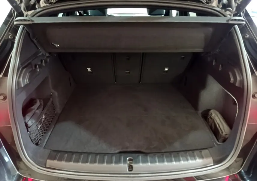 Coffre ouvert vu de l'arrière d'une BMW X1 xDrive23i M Sport noir, montrant un espace de chargement vide et bien fini.