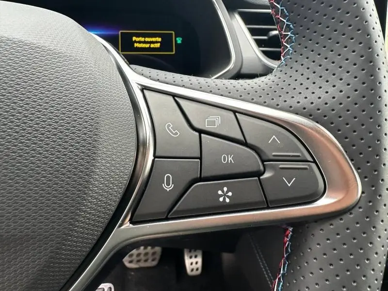 Gros plan sur les commandes multifonctions au volant perforé du Renault Captur 2026 gris Cassiopée/Noir Étoilé.