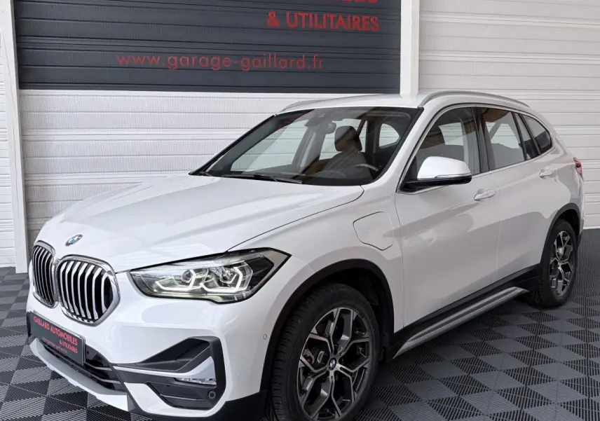 Vue 3/4 avant droite d’un BMW X1 xDrive25eA xLine blanc avec calandre chromée et jantes alliage distinctives.