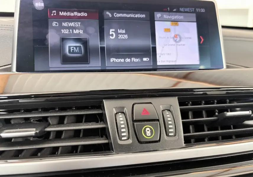 Gros plan sur l’écran tactile central et les commandes de ventilation du tableau de bord du BMW X1 blanc xDrive25eA xLine 2021.