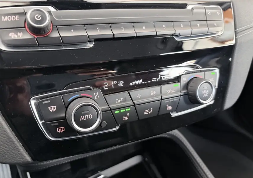 Détail de la console centrale noire du BMW X1 xDrive25eA xLine 2021 montrant les commandes de climatisation automatique et sièges chauffants.
