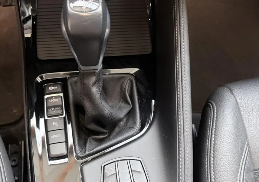 Vue rapprochée de la console centrale noire du BMW X1 xDrive25eA 2021 avec levier de vitesses et commandes multimodes.