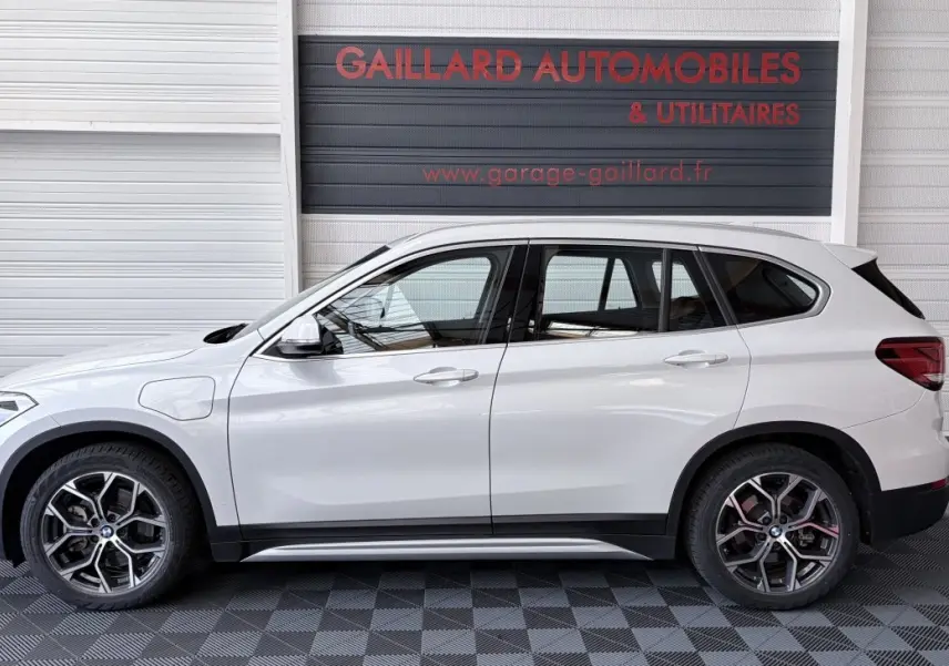 Profil droit d’un BMW X1 blanc hybride rechargeable xDrive25eA xLine 2021, avec jantes alliage et prises de charge latérales.