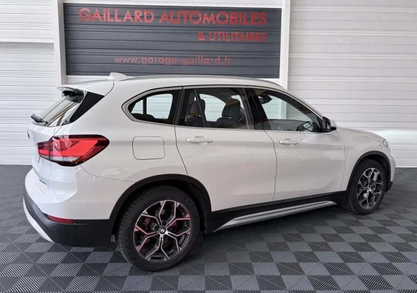 BMW X1 xDrive25eA xLine blanc en vue latérale droite, avec jantes alliage et rails de toit chromés visibles.