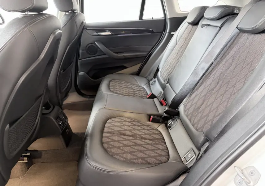 Vue intérieure arrière côté droit montrant les sièges en cuir noir et tissu gris du BMW X1 blanc 2021.
