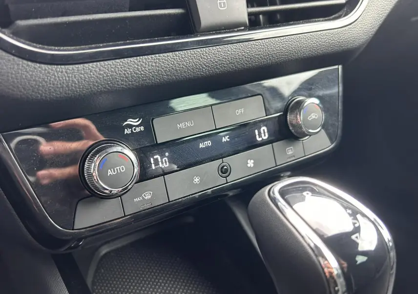 Gros plan sur la console centrale noire du Skoda Scala blanc, montrant la climatisation automatique et le levier de vitesses.