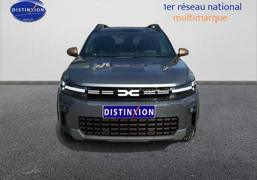 Vue frontale du Dacia Bigster gris schiste avec calandre noire et phares LED fins allumés.
