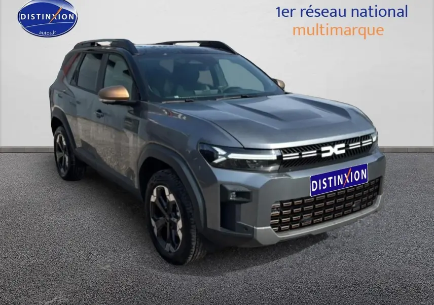 Dacia Bigster gris schiste en 3/4 avant droit, avec barres de toit et jantes alliage distinctives.
