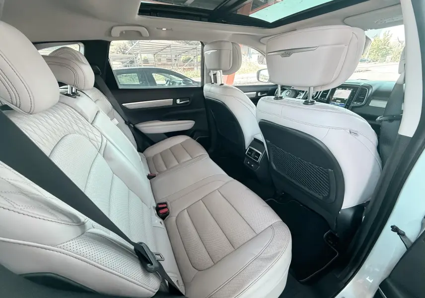Vue intérieure arrière du Renault Koleos blanc 2021, sièges cuir clair avec logo Initiale Paris sur appuie-tête.