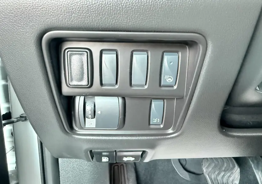 Gros plan sur les commandes de réglage des phares et du volant chauffant dans un Renault Koleos blanc, intérieur noir.