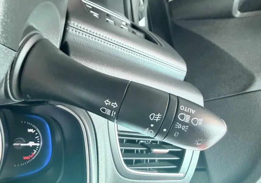 Gros plan sur la commande des phares et clignotants du Renault Koleos TCE 160 Initial Paris, intérieur noir.