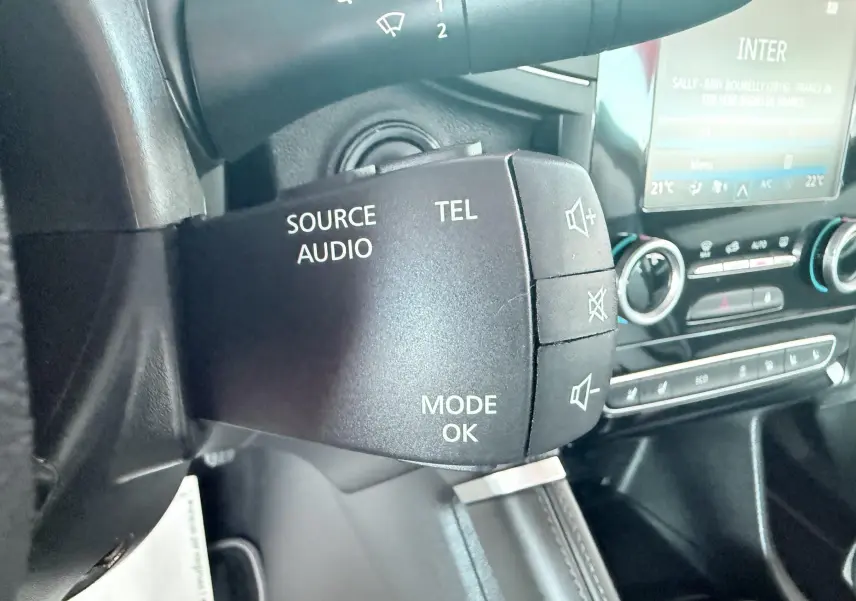 Gros plan sur la commande audio au volant du Renault Koleos 2021, intérieur noir avec tableau de bord et écran tactile.