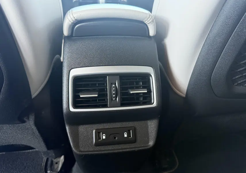 Vue rapprochée de la console centrale arrière noire avec aérateurs et ports USB du Renault Koleos blanc 2021.