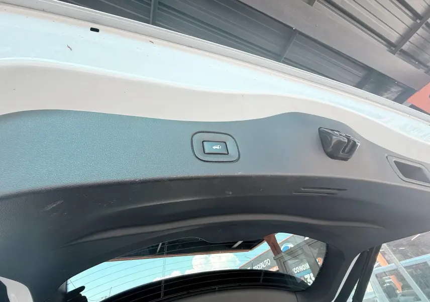 Vue intérieure du hayon blanc du Renault Koleos TCE 160 Initial Paris avec bouton d'ouverture électrique visible.