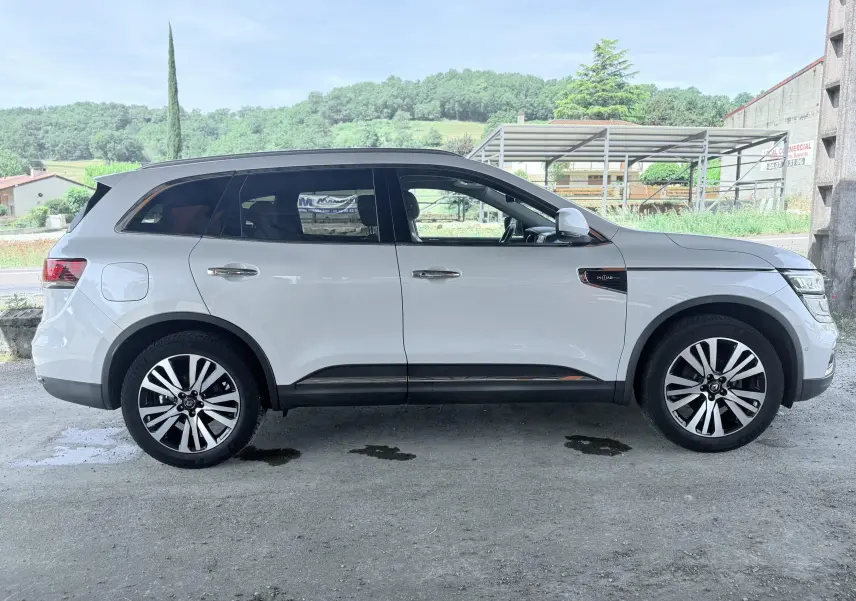 Profil droit d’un Renault Koleos blanc avec toit noir et jantes alliage, version Initial Paris 2021.