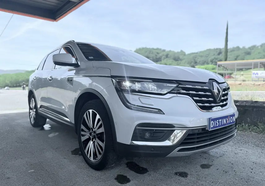 Renault Koleos blanc en 3/4 avant droit, avec calandre chromée et jantes alliage distinctives.