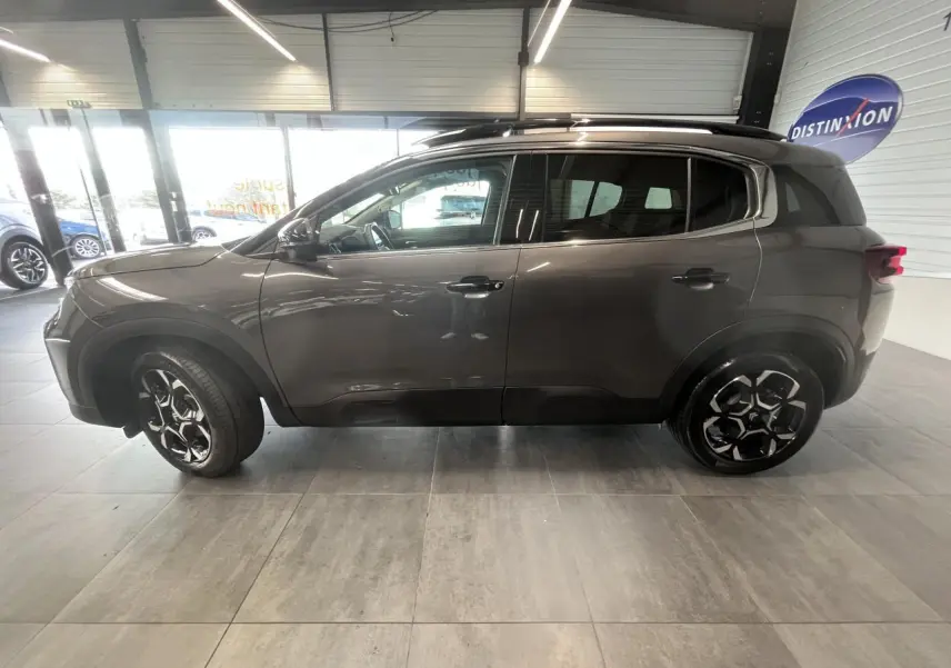 Profil droit du Citroën C5 Aircross gris platinium avec jantes alliage bi-ton et barres de toit noires.