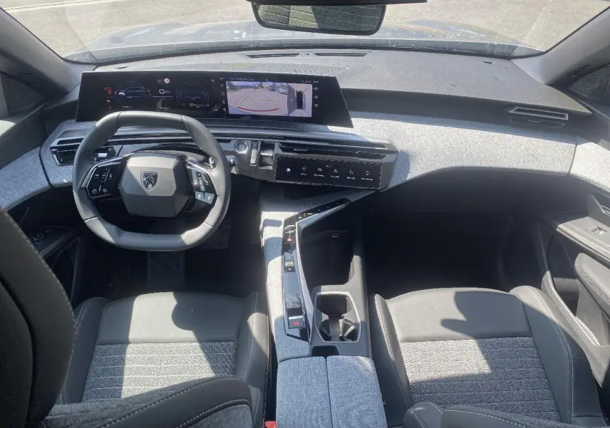Vue intérieure avant du Peugeot 3008 2025 hybride, avec tableau de bord numérique et sellerie tissu gris clair.
