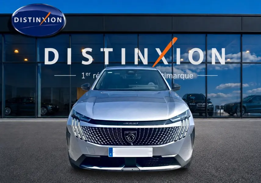 Vue frontale d’un Peugeot 3008 gris 2025 avec calandre distinctive et logo lion, devant une vitrine Distinxion.