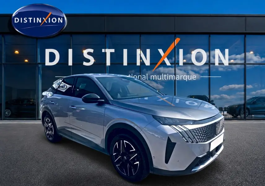 Peugeot 3008 gris en 3/4 avant droit, avec calandre distinctive et jantes alliage noires devant un showroom.