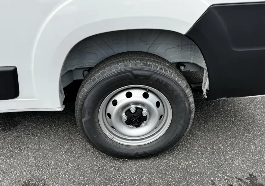 Gros plan sur la roue avant droite du Peugeot Boxer Fourgon blanc, avec jante acier et logo Peugeot central.