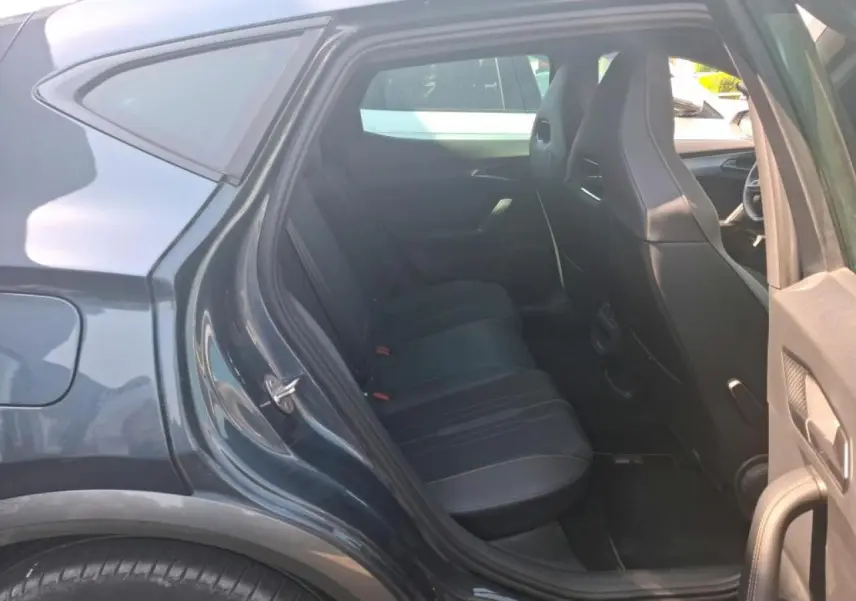 Vue côté gauche arrière sur l'intérieur du CUPRA Formentor gris, montrant les sièges arrière en textile noir et les portes ouvertes.