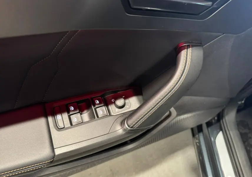 Détail de la porte côté conducteur du Cupra Formentor gris, avec commandes de vitres et poignée en cuir surpiqué.